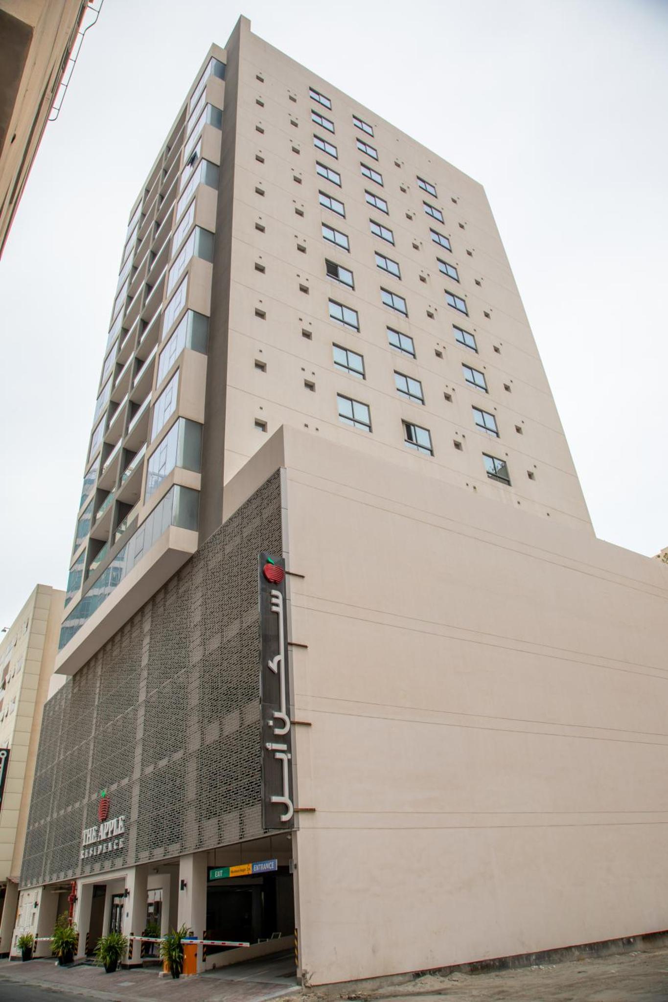 a tall white building with a sign on it at The Apple Residence in Juffair