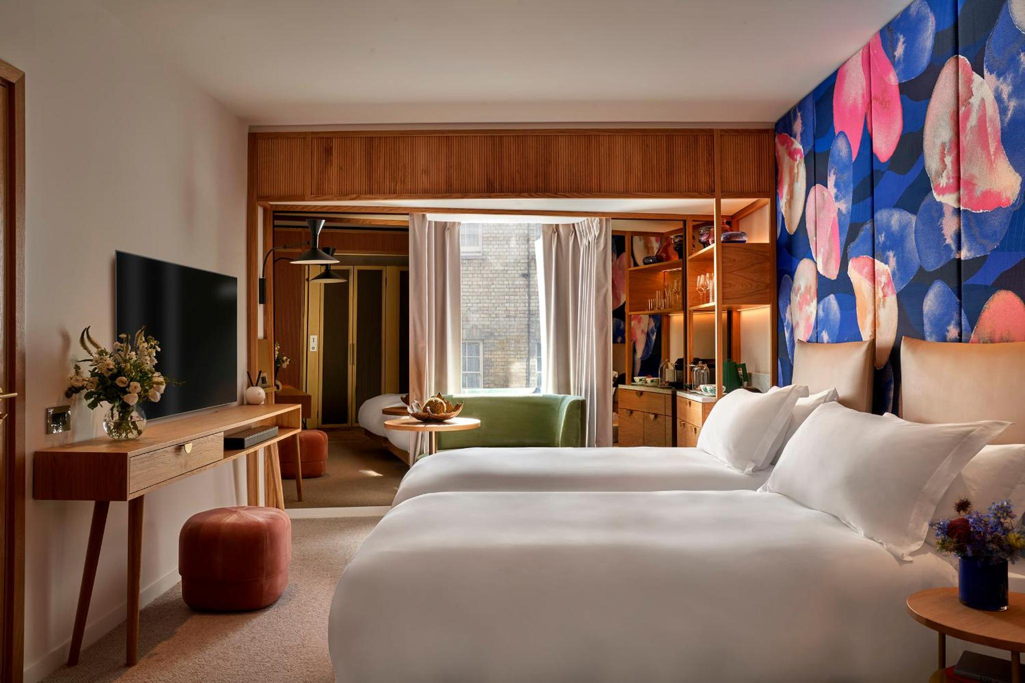 a hotel room with two beds and a television at The BoTree London, Curio Collection by Hilton in London