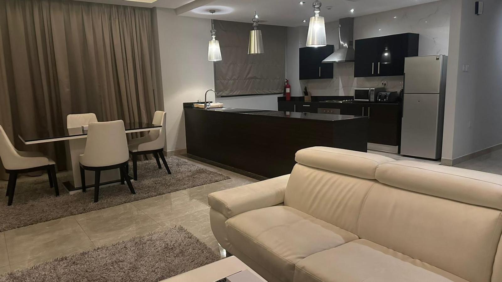 a living room and kitchen with a couch and a table at seef manzil in Seef