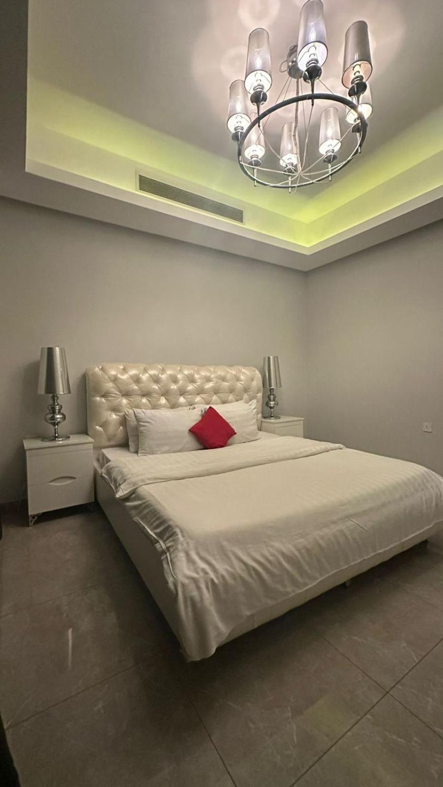 a bedroom with a large white bed with a chandelier at seef manzil in Seef +18 photos