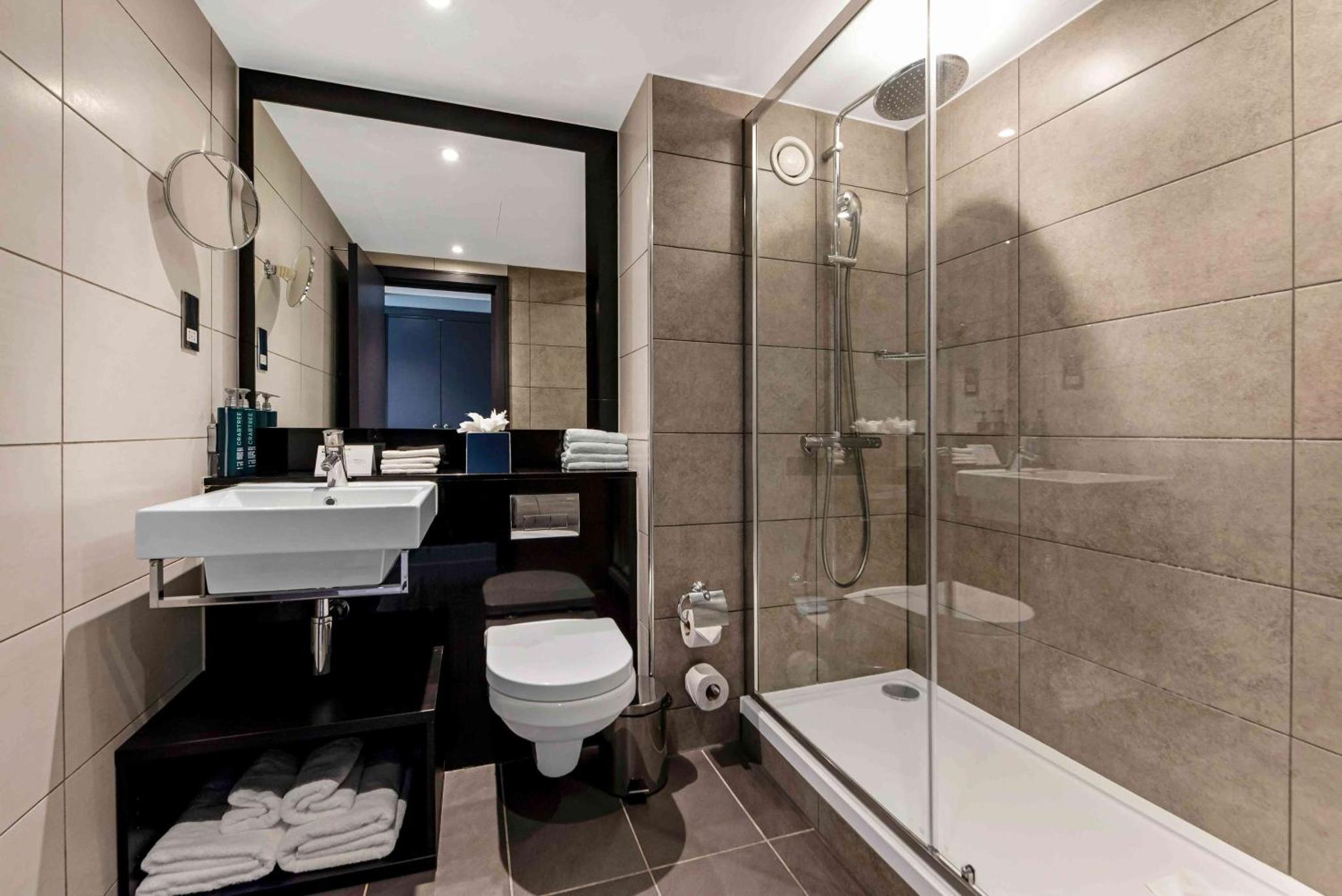 a bathroom with a toilet and a sink and a shower at Doubletree By Hilton London Kensington in London