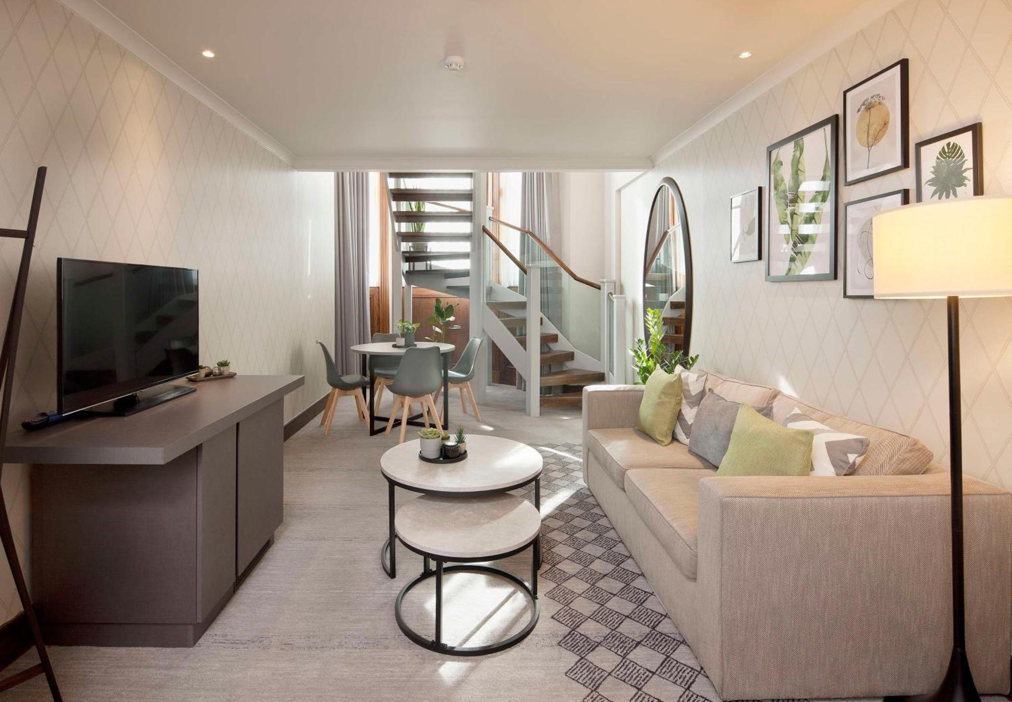a living room with a couch and a tv at Doubletree By Hilton London Kensington in London