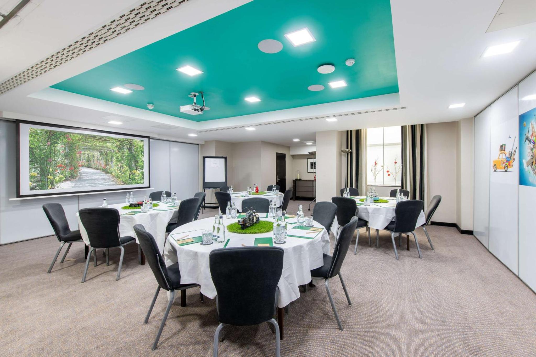 a conference room with tables and chairs and a green ceiling at Doubletree By Hilton London Kensington in London