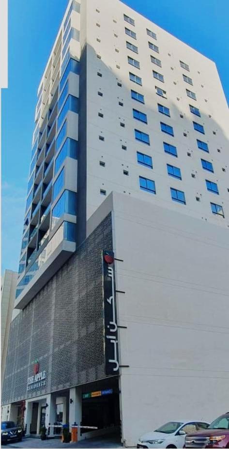 a large white building with a car parked in front of it at The Apple Residence in Juffair