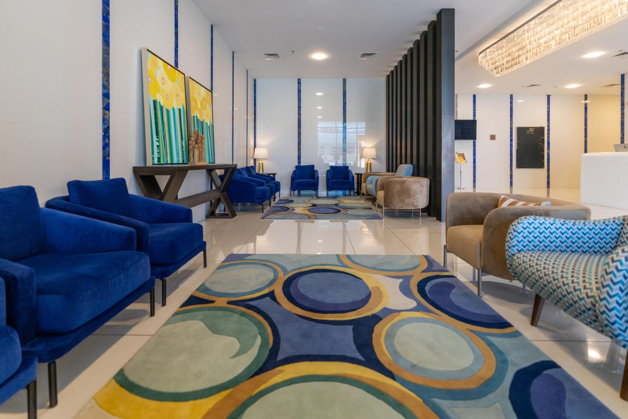 a waiting room with blue chairs and a rug at S Plaza Suites Hotel in Manama