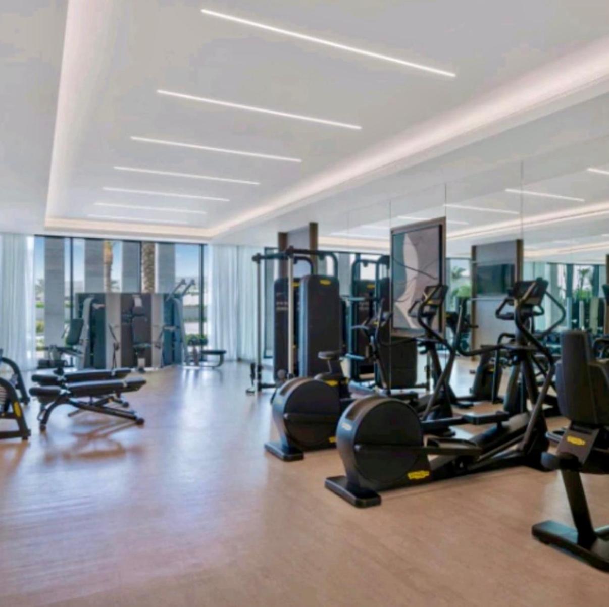 a gym with lots of treadmills and exercise bikes at شقق فندقية خاصة في منتجع العنوان الشاطئي - مراسي البحرين in Rayyā