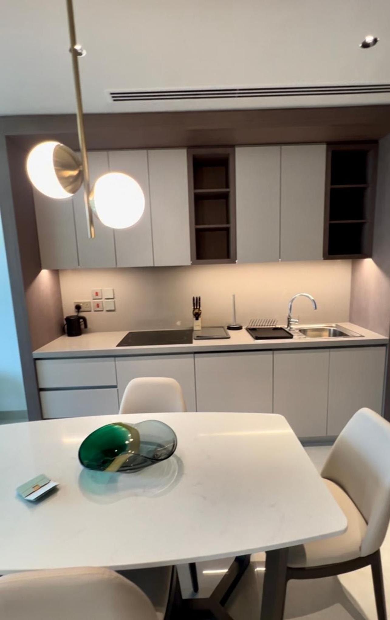 a kitchen with a white table and white chairs at شقق فندقية خاصة في منتجع العنوان الشاطئي - مراسي البحرين in Rayyā