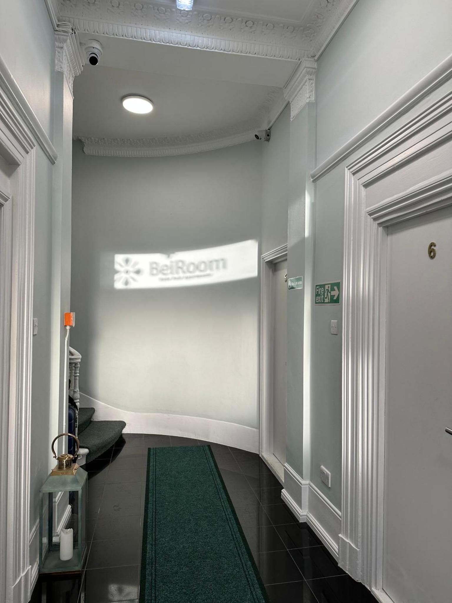 a hallway with a green rug in a building at BeiRoom Hyde Park Apartments in London