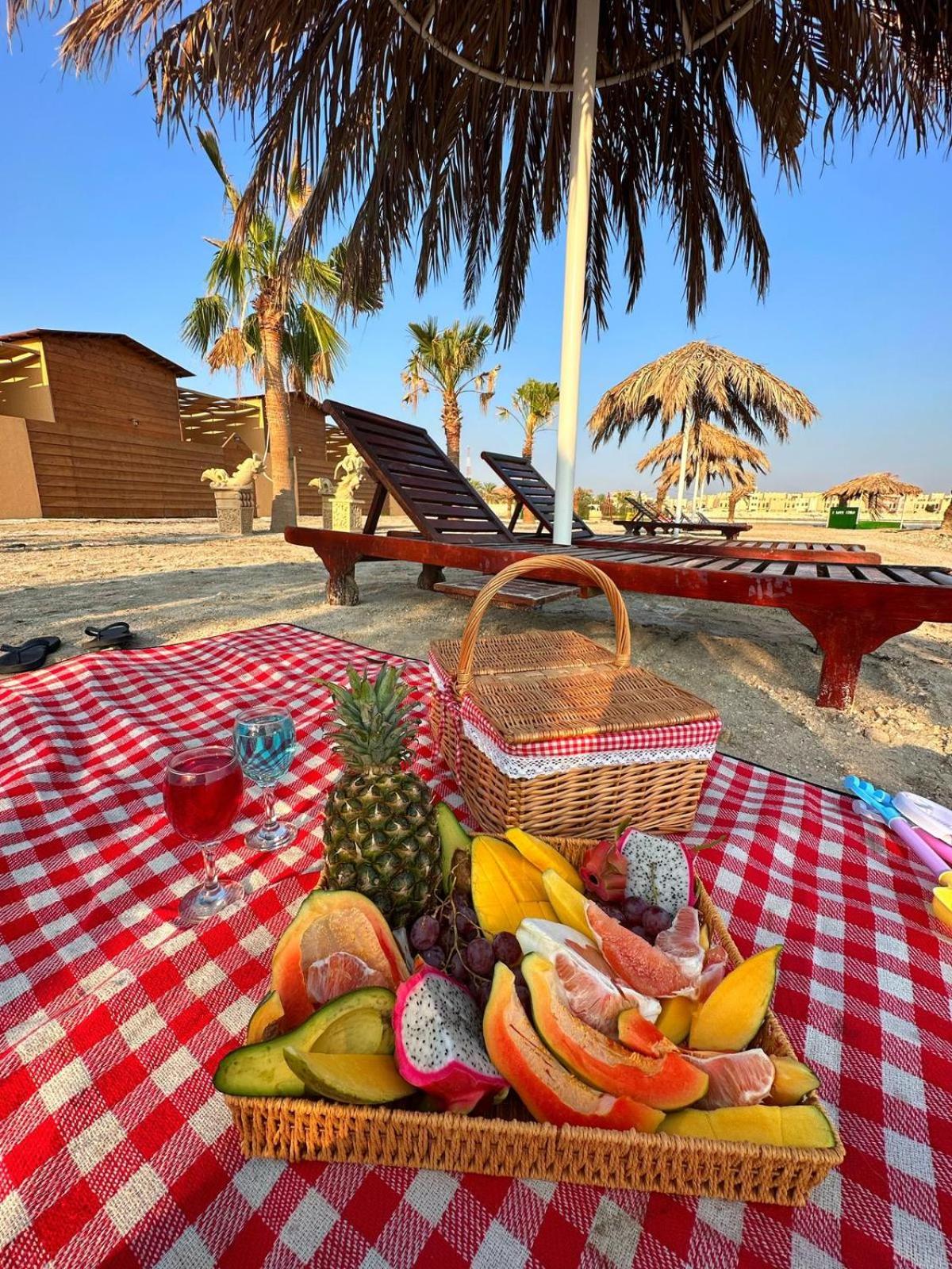 a picnic table with a basket of fruit and a glass of wine at Cielo Beach Resort in Al Qaryah +59 photos