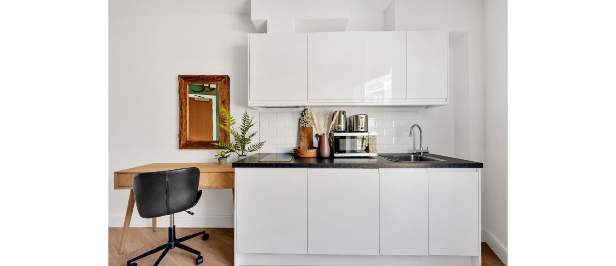 a kitchen with white cabinets and a sink and a chair at Cozy and Lovely Studio - Close to everything! in London +11 photos