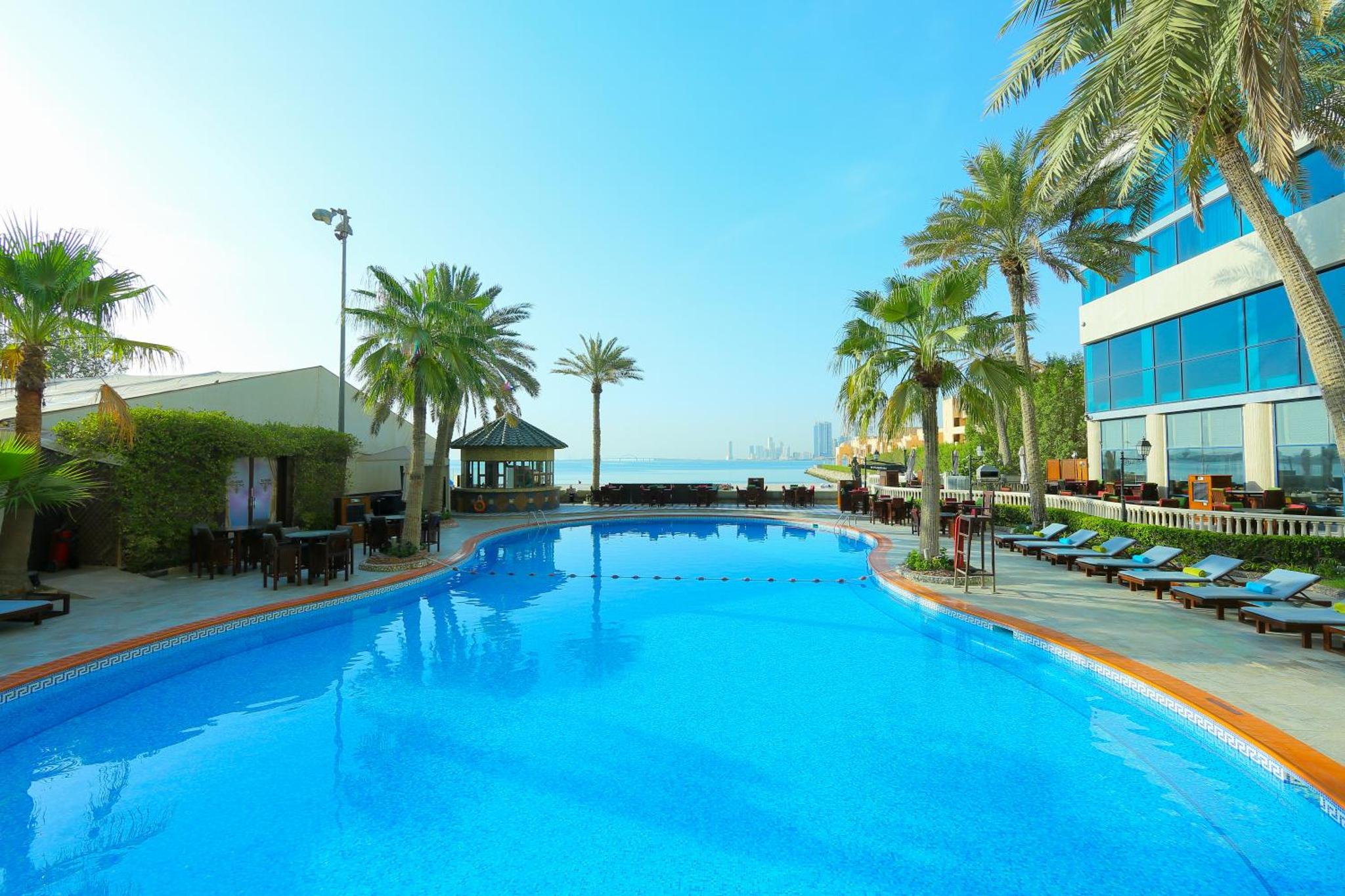 a large swimming pool with palm trees and a building at Elite Resort & Spa in Manama +37 photos