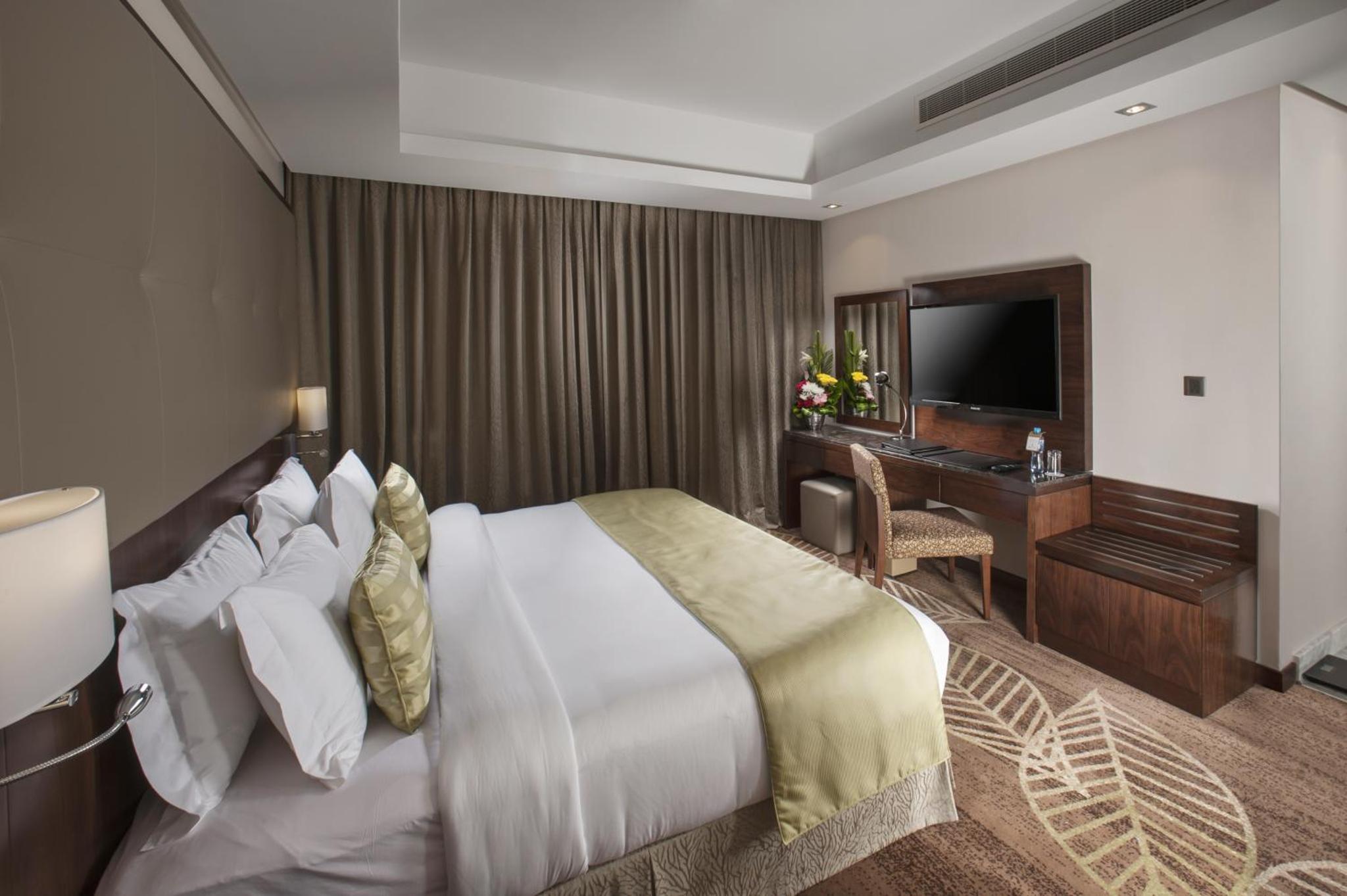 a hotel room with a bed and a desk at Ramee Rose Hotel in Manama