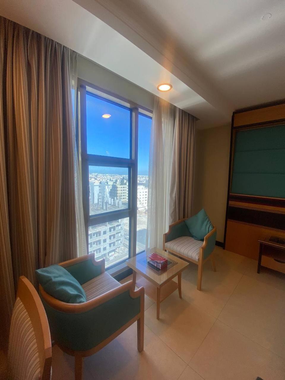 a living room with a large window and a flat screen tv at Nooh Apartment in Al Ḩadd