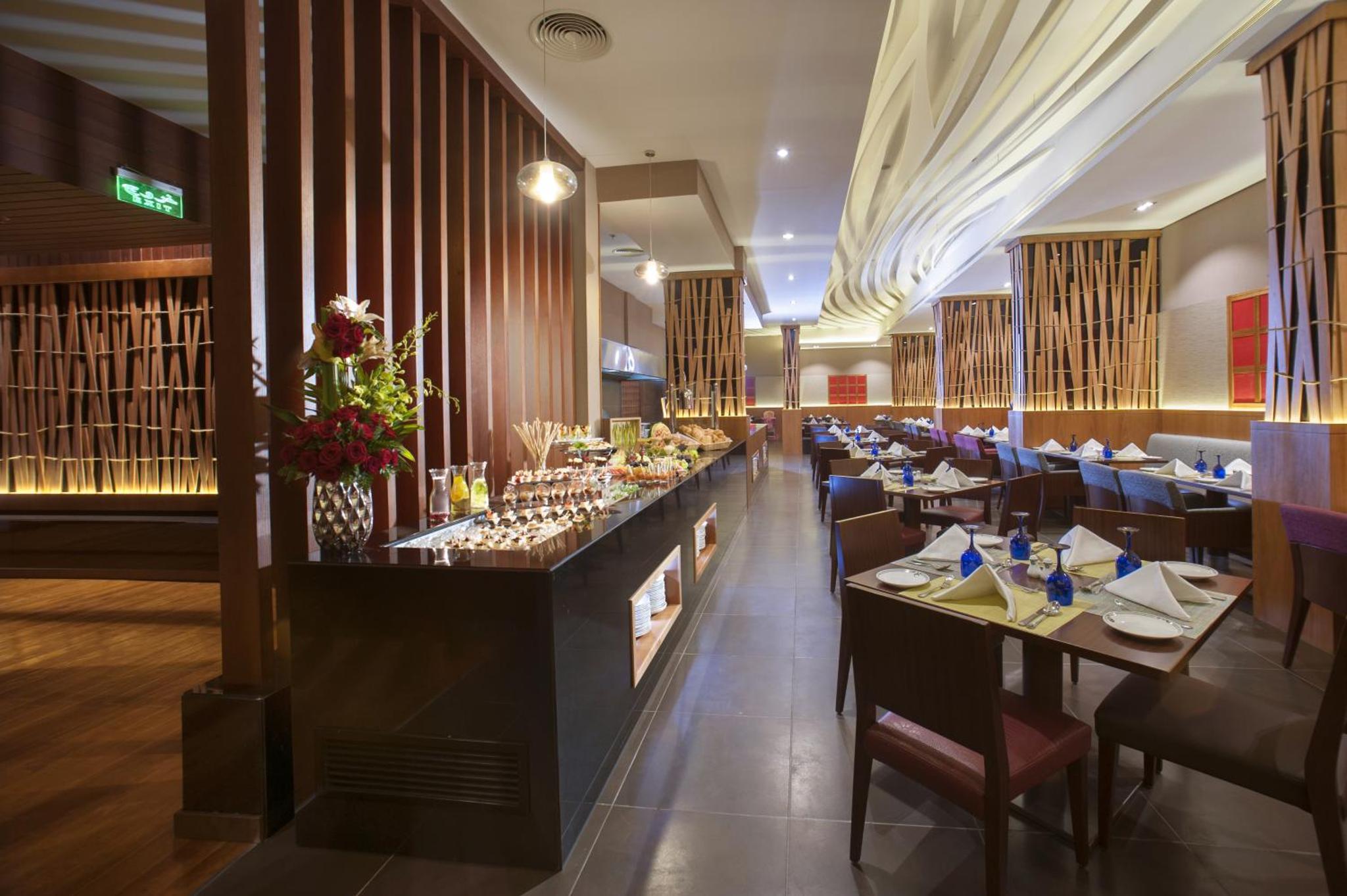 a restaurant with tables and chairs and a bar at Ramee Rose Hotel in Manama
