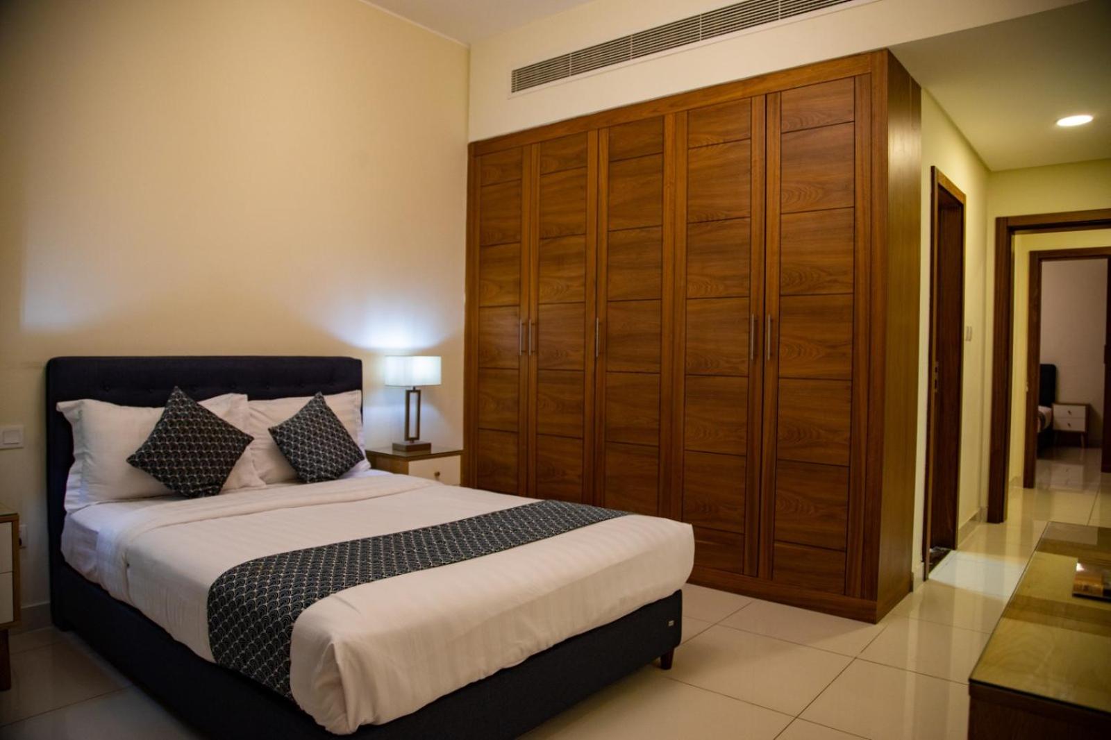 a bedroom with a bed and a large wooden closet at Ginger Luxury House in Juffair