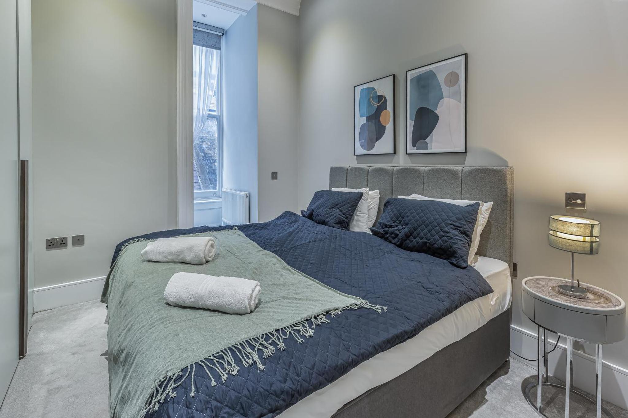 a bedroom with a large bed with blue sheets and pillows at Green Street Residences by Aeria Apartments in London