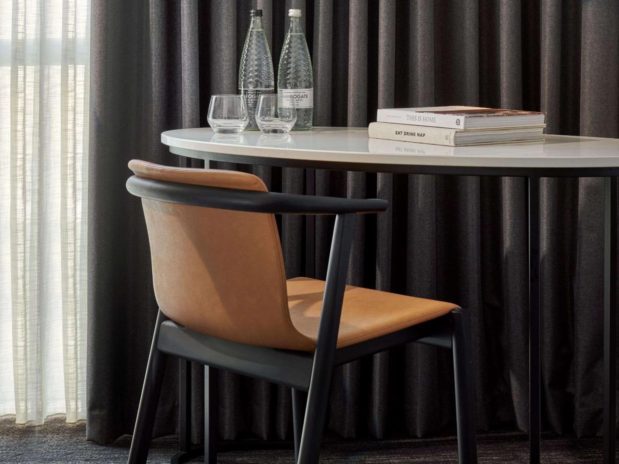 a table with a chair and wine glasses and books at Hyatt Regency London Stratford in London