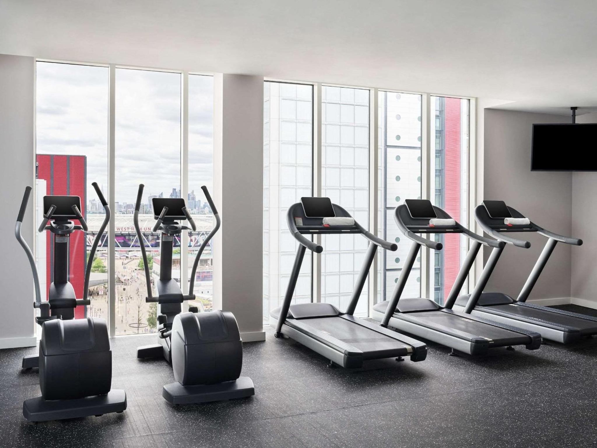 a gym with cardio equipment in a room with a large window at Hyatt Regency London Stratford in London