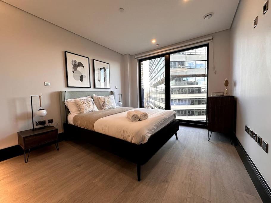 a bedroom with a large bed and a large window at The Glamour of Shoreditch in London