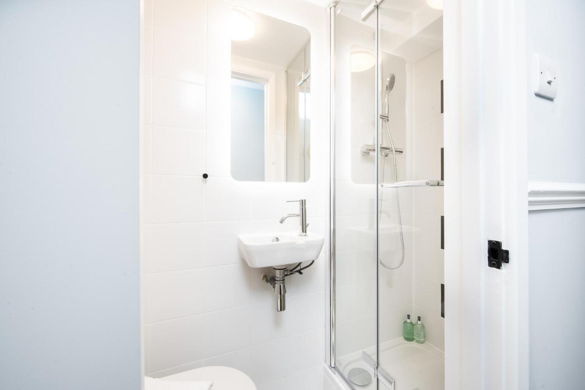 a white bathroom with a sink and a shower at Americana Hotel in London