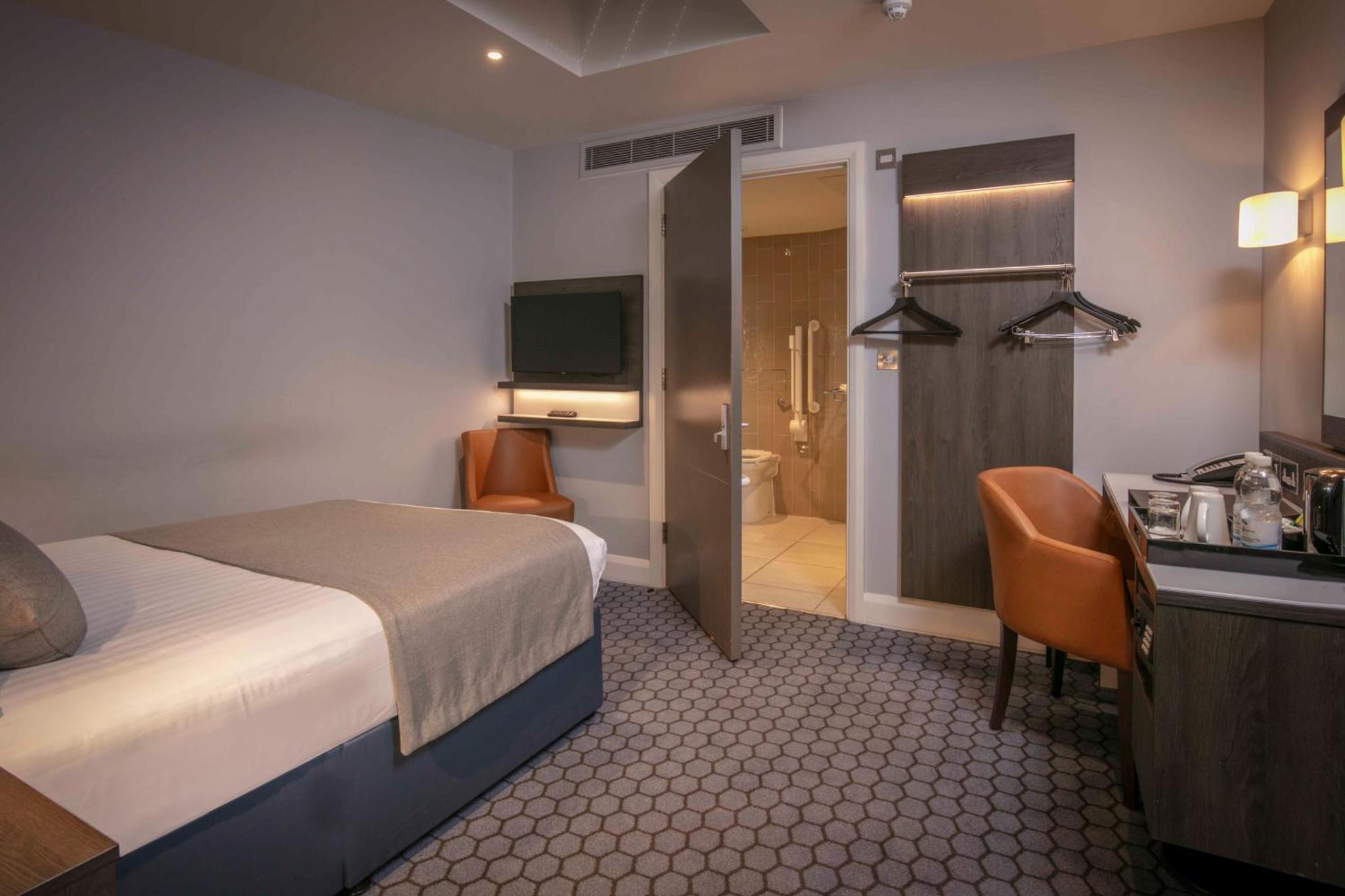 a hotel room with a bed and a bathroom at Best Western Plus Vauxhall Hotel in London