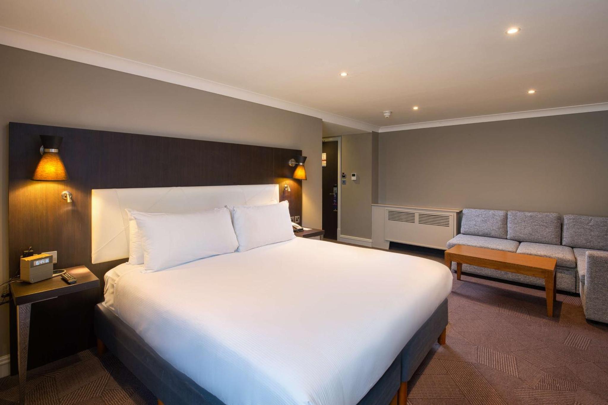 a hotel room with a large bed and a couch at DoubleTree by Hilton London Ealing in London