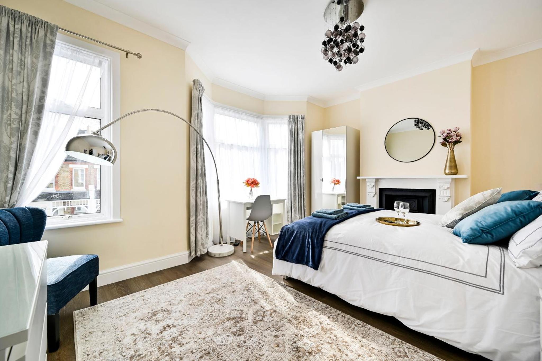 a white bedroom with a bed and a fireplace at A two bedroom a stride away from Meridian Greenwich in London