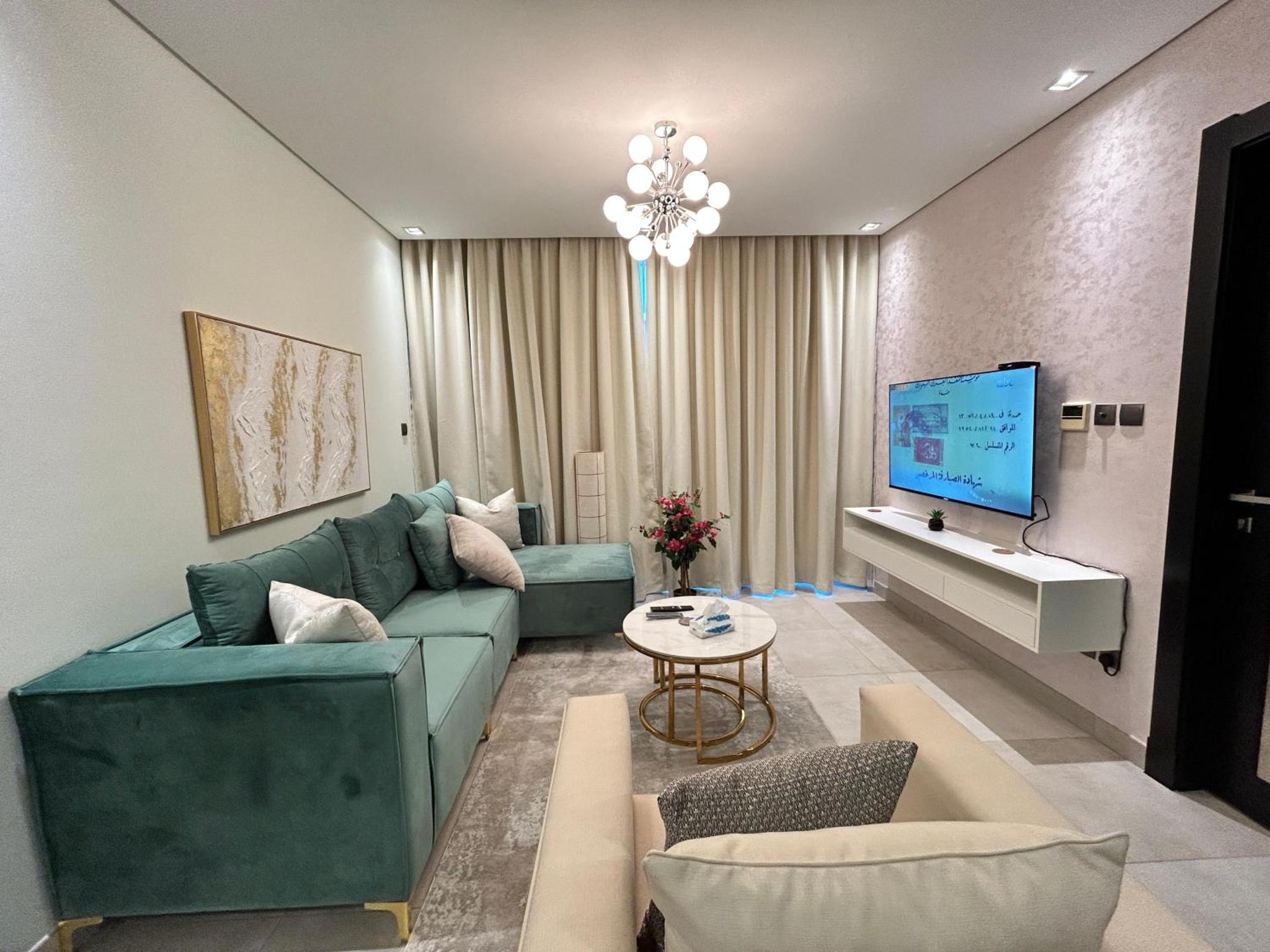 a living room with a green couch and a tv at Luxury Romantic Sea View Apartment-ERAإقامة هادئة إطلالة بحرية موقع استثنائي- Manama in Manama