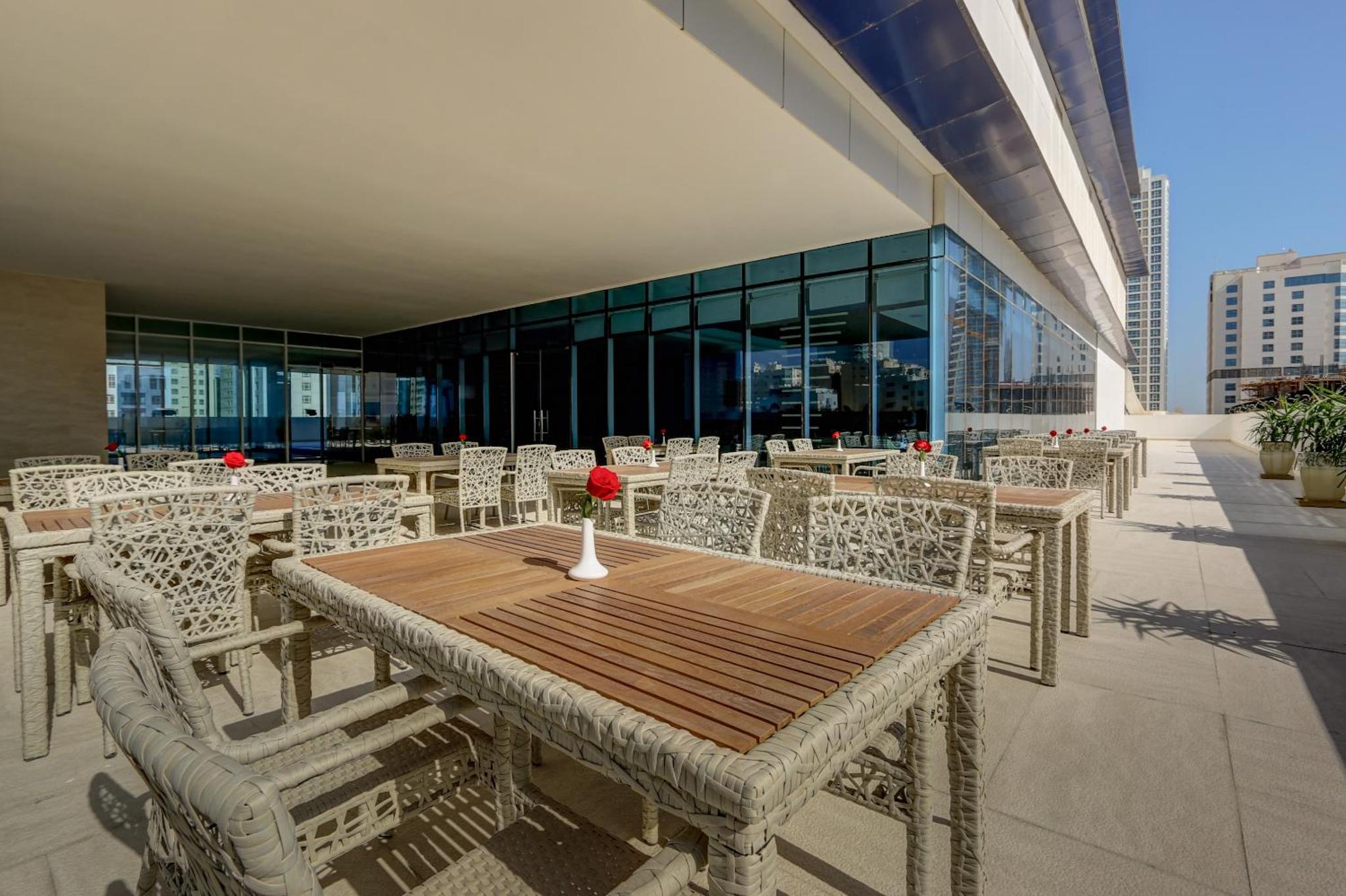 a wooden table and chairs on a building patio at Premier Hotel in Manama