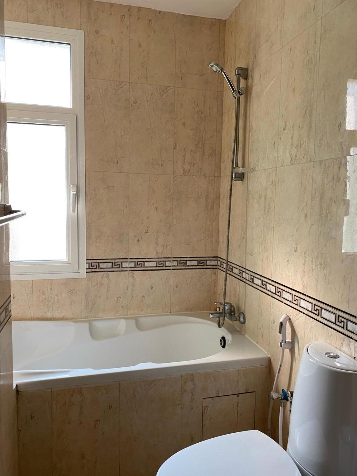 a bathroom with a tub and a toilet and a window at Blue Horizon Suites in Manama +64 photos