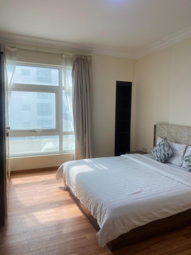 a bedroom with a large bed and a large window at Blue Horizon Suites in Manama