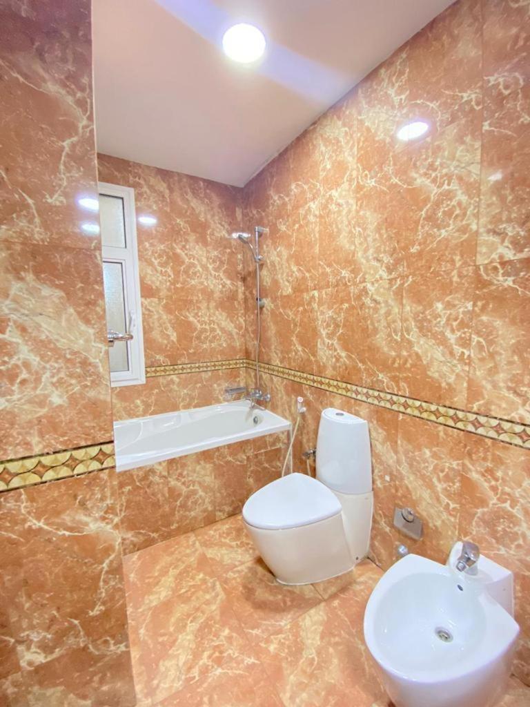 a bathroom with a toilet and a sink and a tub at Blue Horizon Suites in Manama