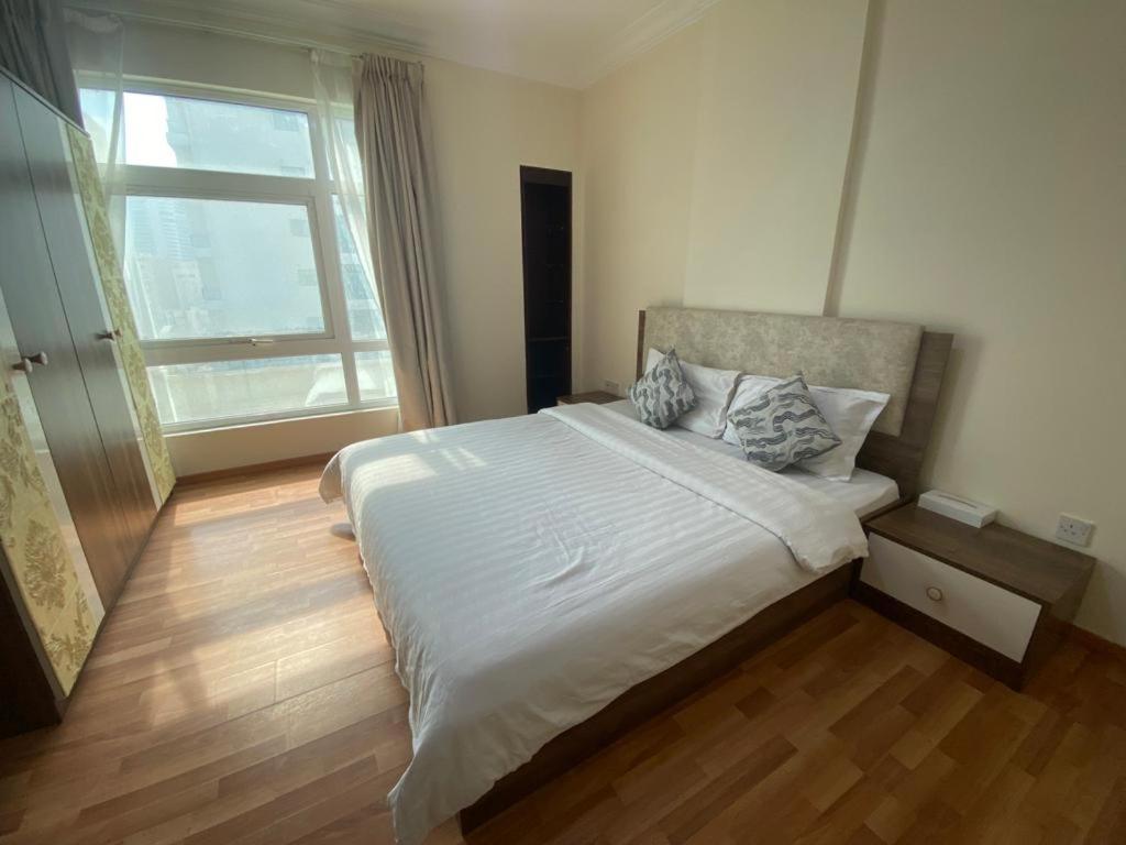 a bedroom with a large white bed and a window at Blue Horizon Suites in Manama