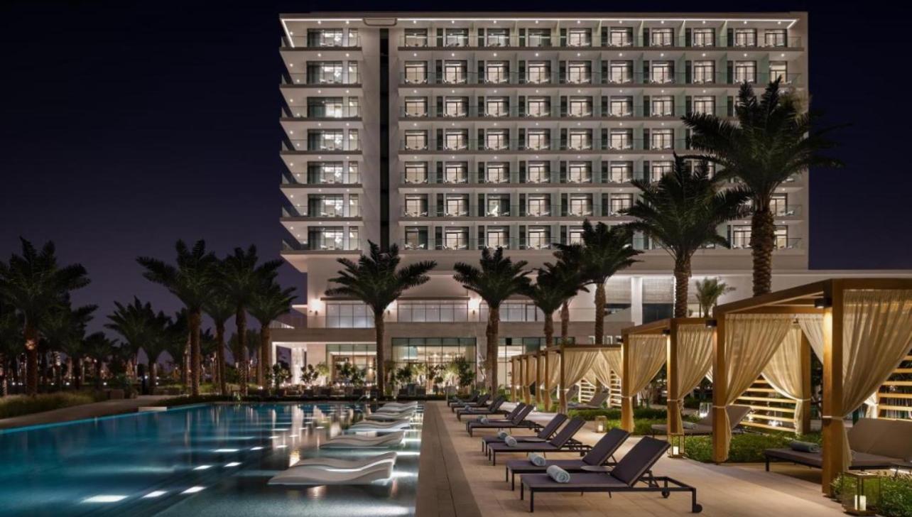a hotel pool with chaise lounge chairs and a building at شقق فندقية خاصة في منتجع العنوان الشاطئي - مراسي البحرين in Rayyā