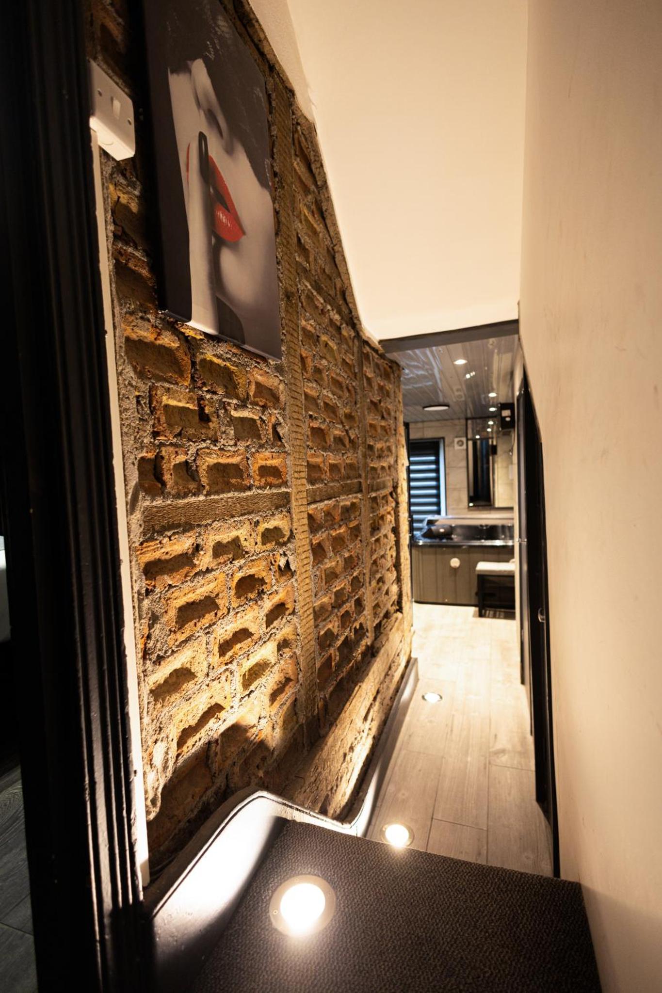 a hallway with a brick wall with a red shoe on it at Sizzling London Studio with Jacuzzi & Private Bath in London