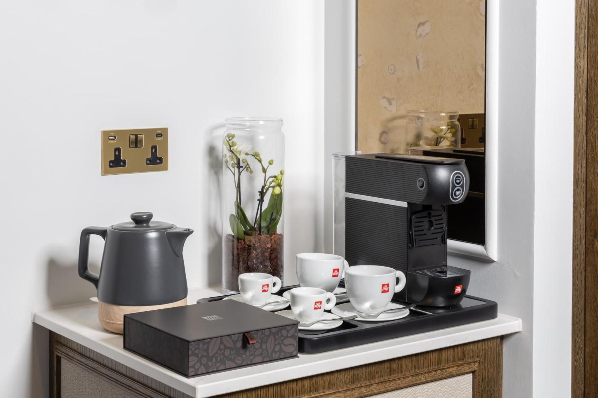 a counter with a coffee maker and cups on it at The Welbeck Hotel by IHG in London