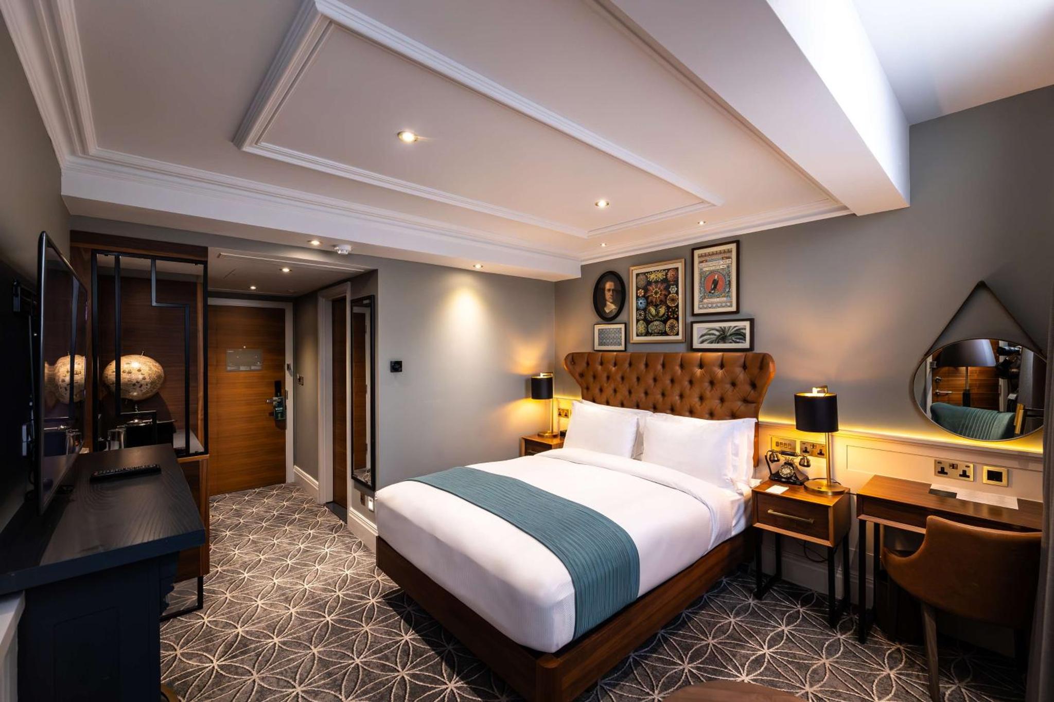 a bedroom with a bed and a desk and a television at 100 Queen's Gate Hotel London Kensington, Curio Collection by Hilton in London