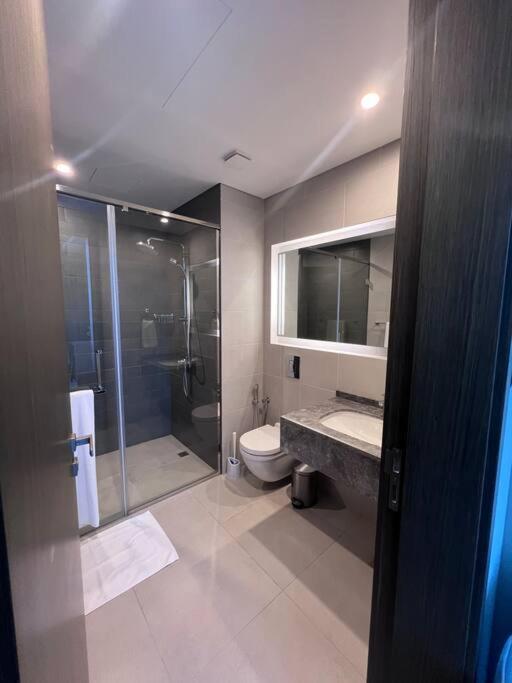 a bathroom with a shower and a toilet and a sink at Cozy Stay in Manama