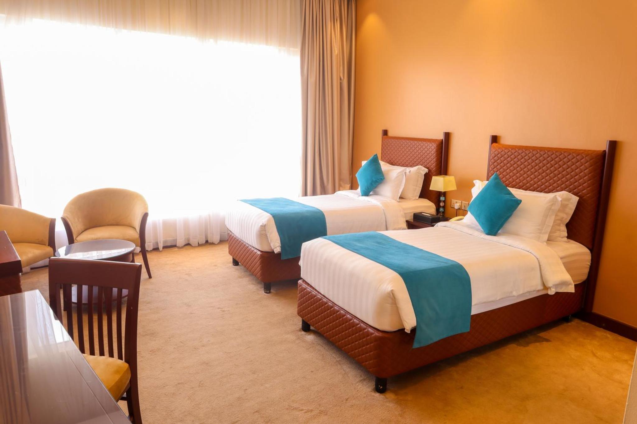 a hotel room with two beds and a window at Palette Luxury Marina View Formerly Happy Days Hotel in Manama