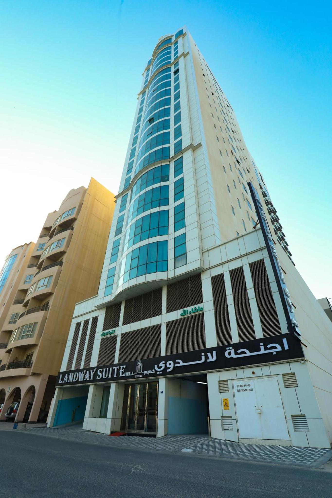 a tall building with a sign in front of it at Landway Suite in Manama