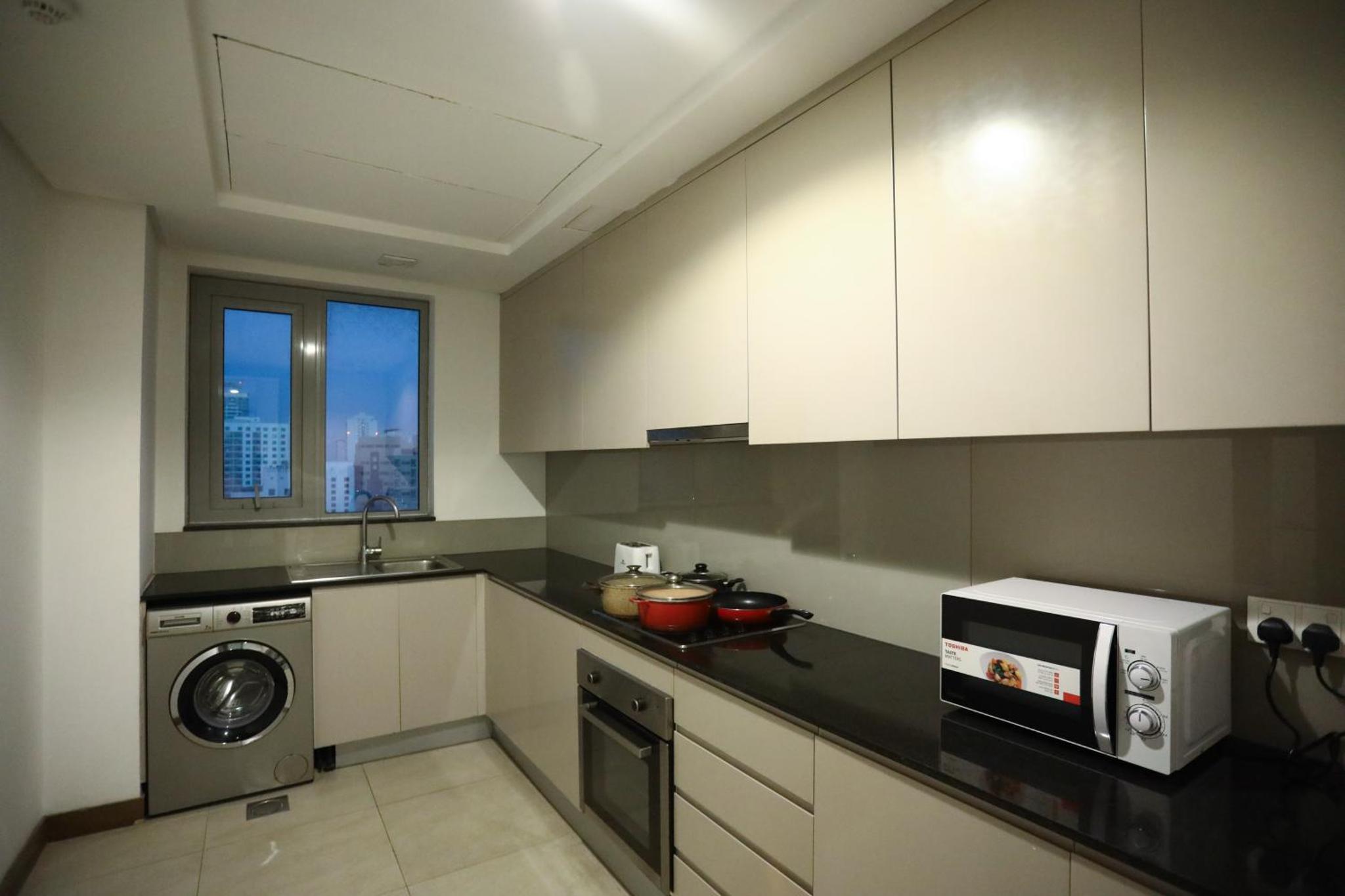 a kitchen with a washing machine and a microwave at Landway Suite in Manama