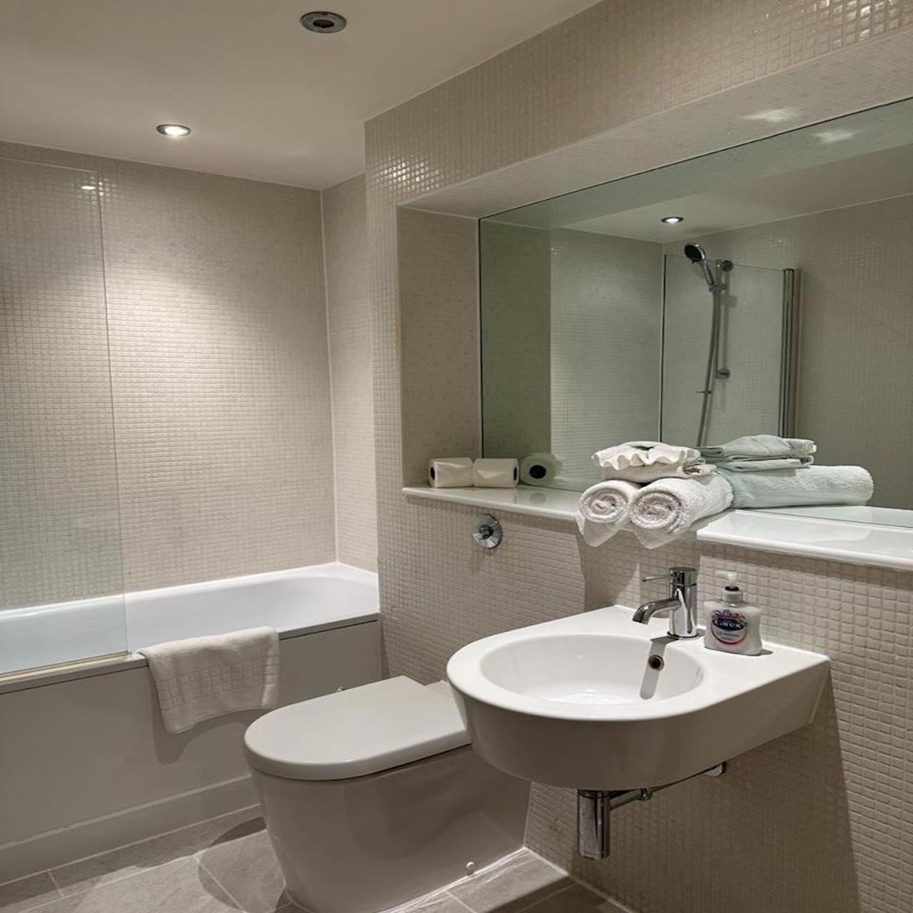 a bathroom with a sink and a toilet and a mirror at Canary Wharf - Luxury Apartments in London