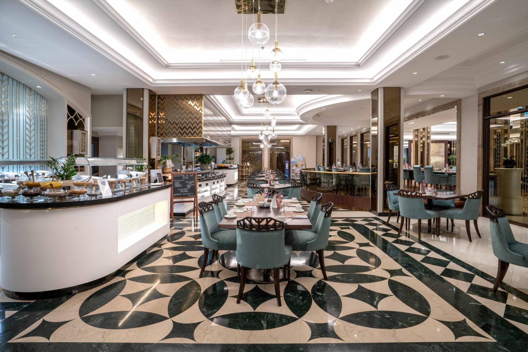 a hotel lobby with a restaurant with tables and chairs at The Diplomat Radisson Blu Residence in Manama