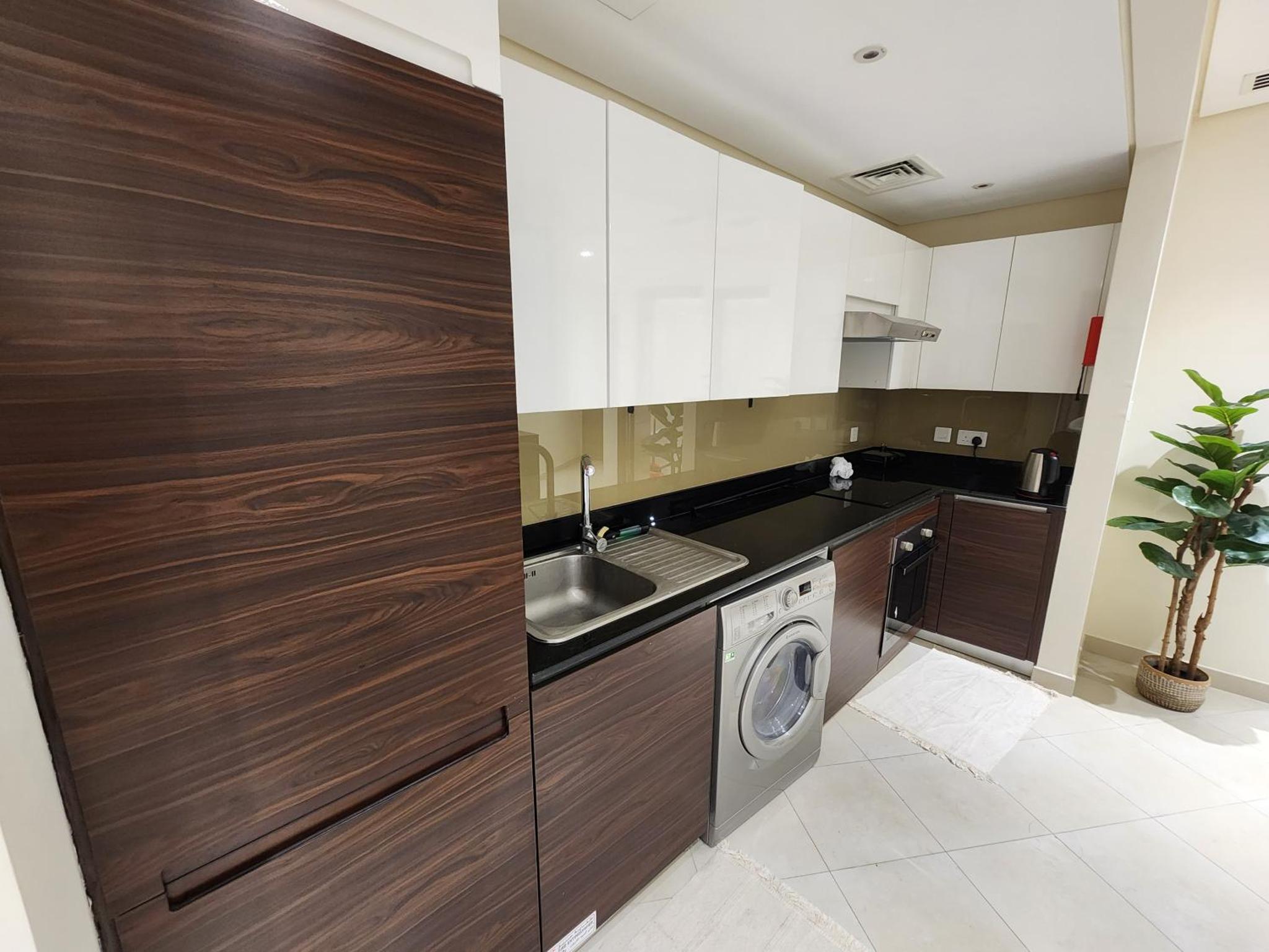 a kitchen with a sink and a washing machine at Premium Garden View Studio Harbour Heights in Manama