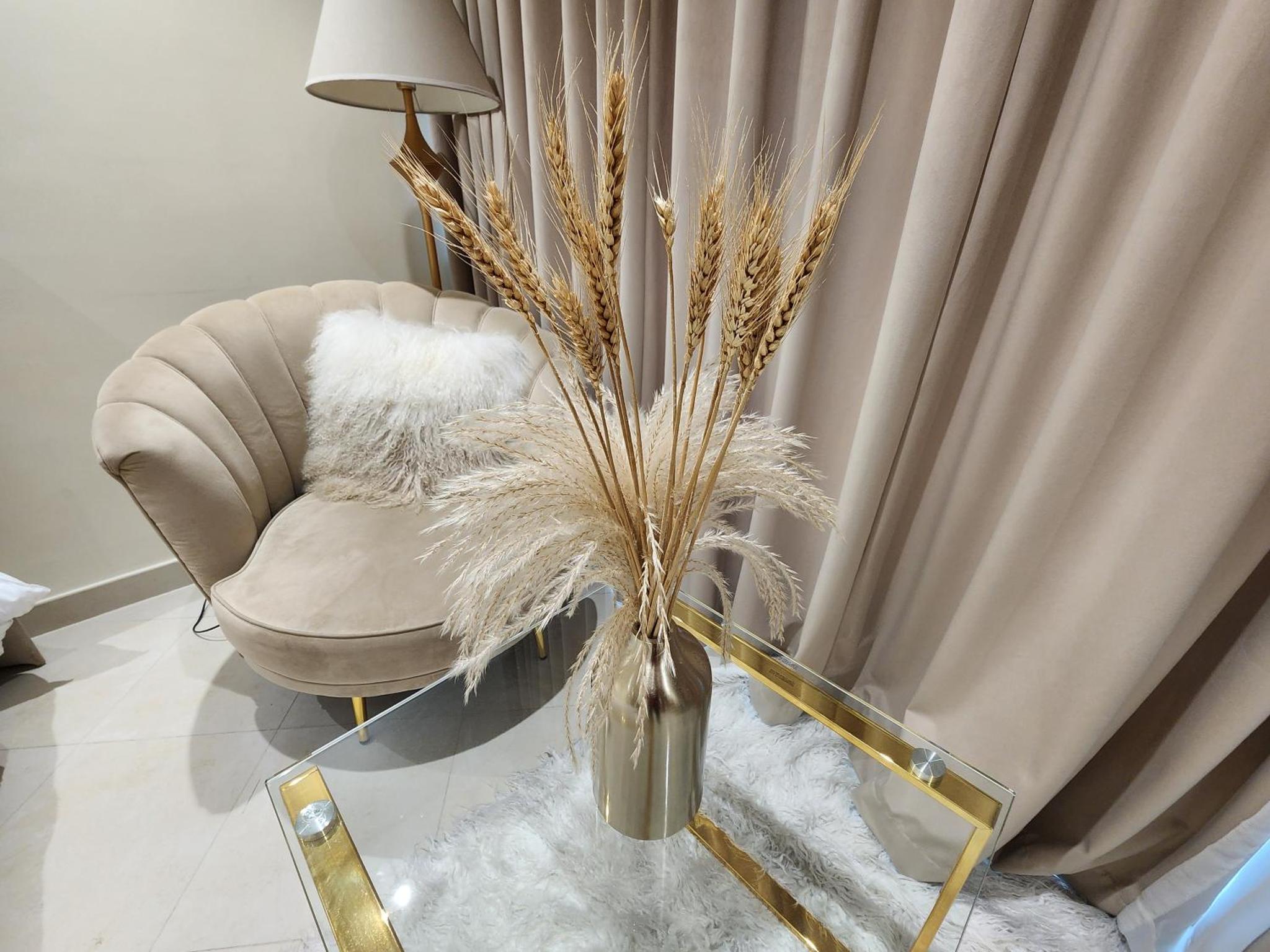 a living room with a chair and a vase with grass at Premium Garden View Studio Harbour Heights in Manama