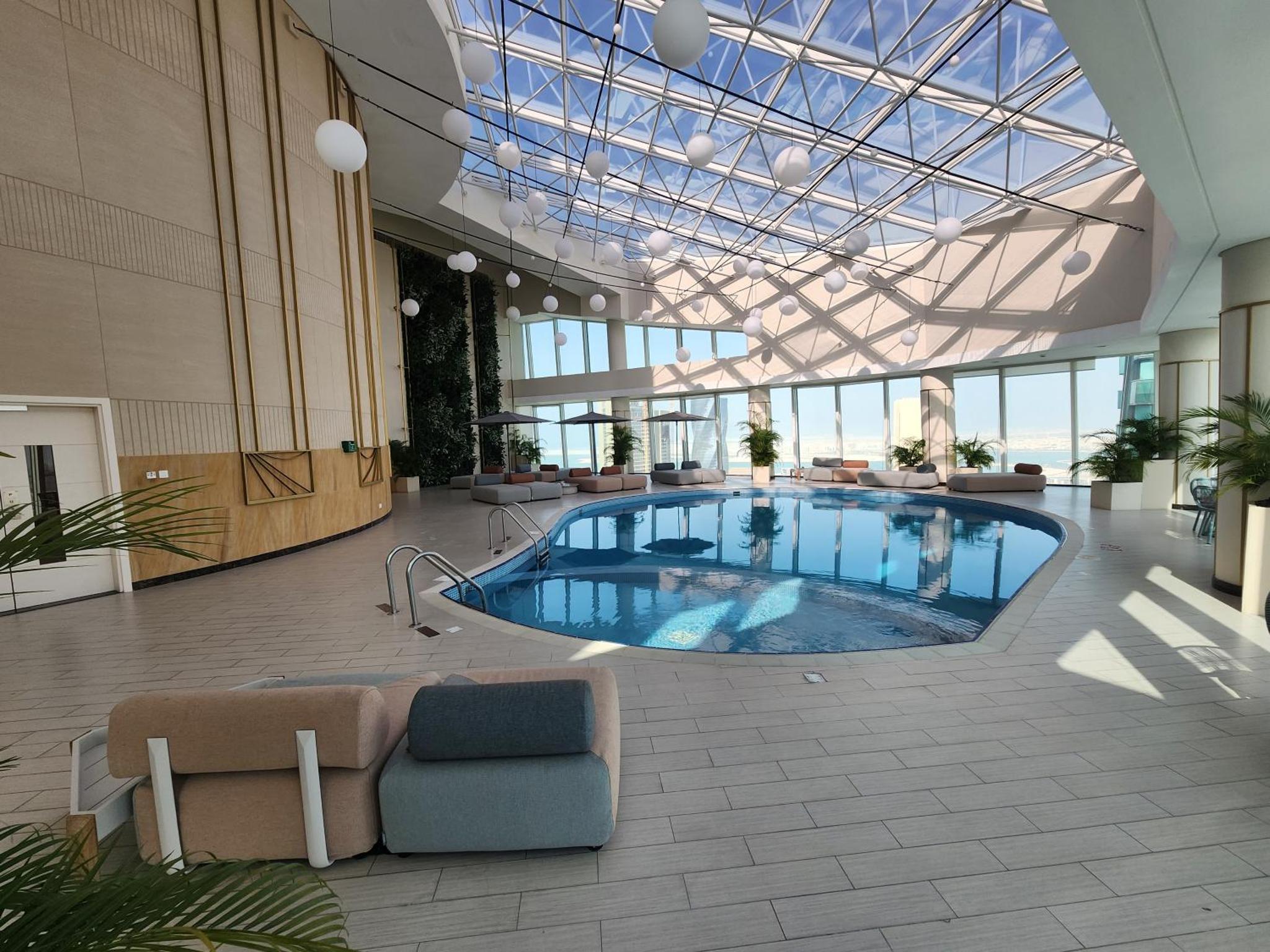 a large indoor pool in a building with a glass ceiling at Premium Garden View Studio Harbour Heights in Manama
