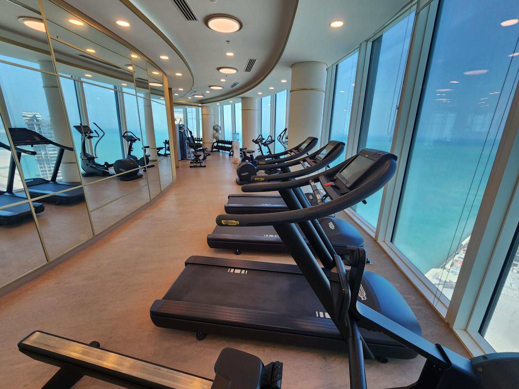a row of treadmills in a gym with windows at Premium Garden View Studio Harbour Heights in Manama