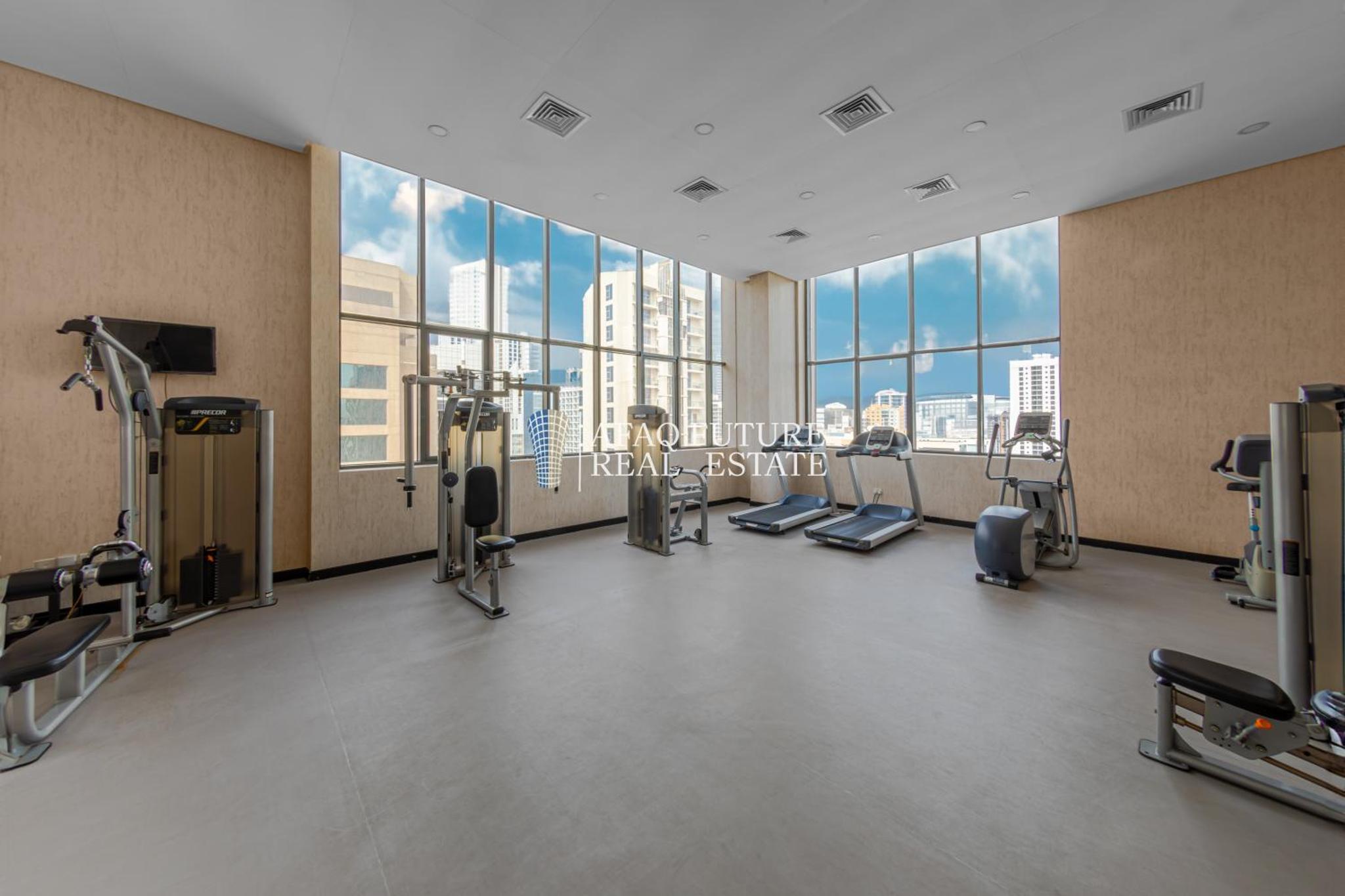 a gym with a large window and tread machines at Vita Tower in Manama