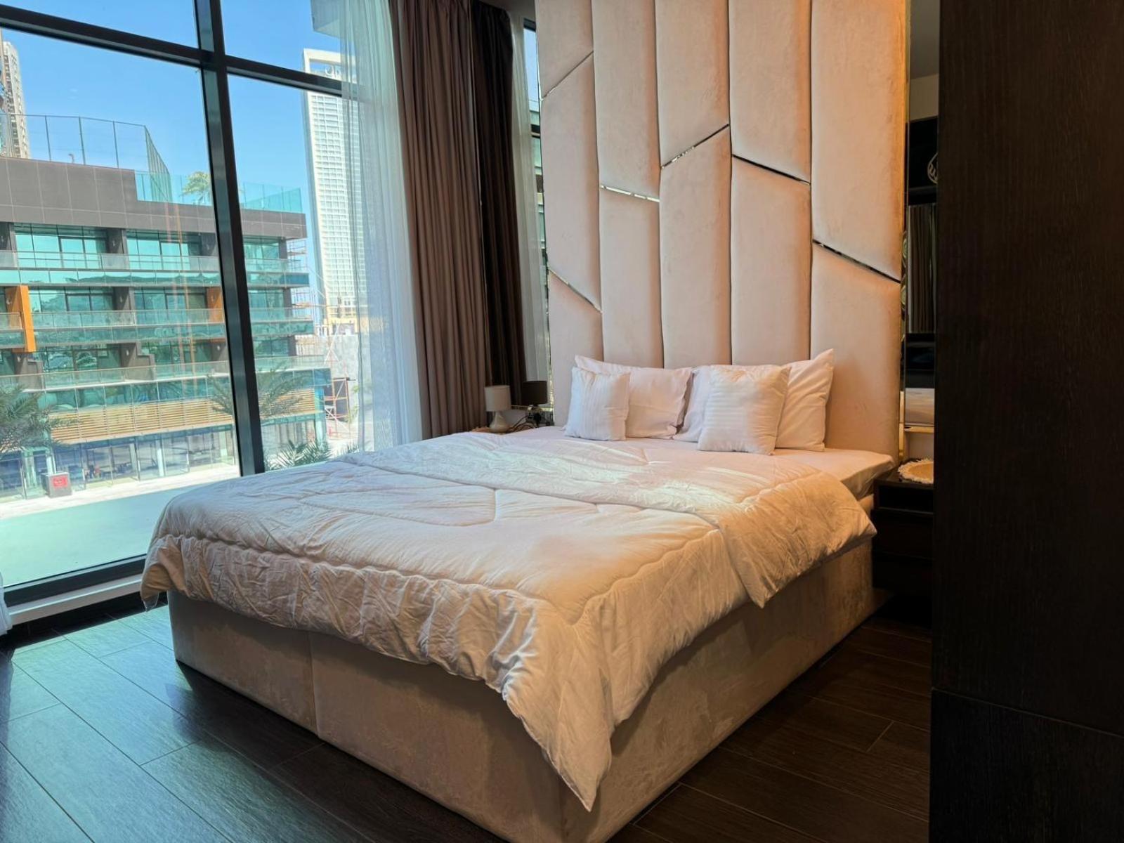 a bedroom with a large bed with a large window at Harbor Row in Manama