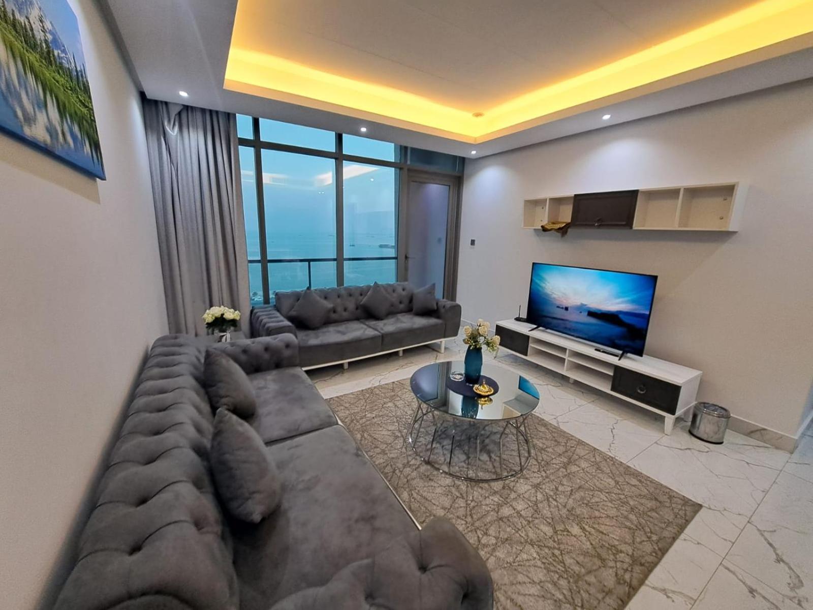 a living room with a large couch and a television at Al Safwa One in Al Ḩadd